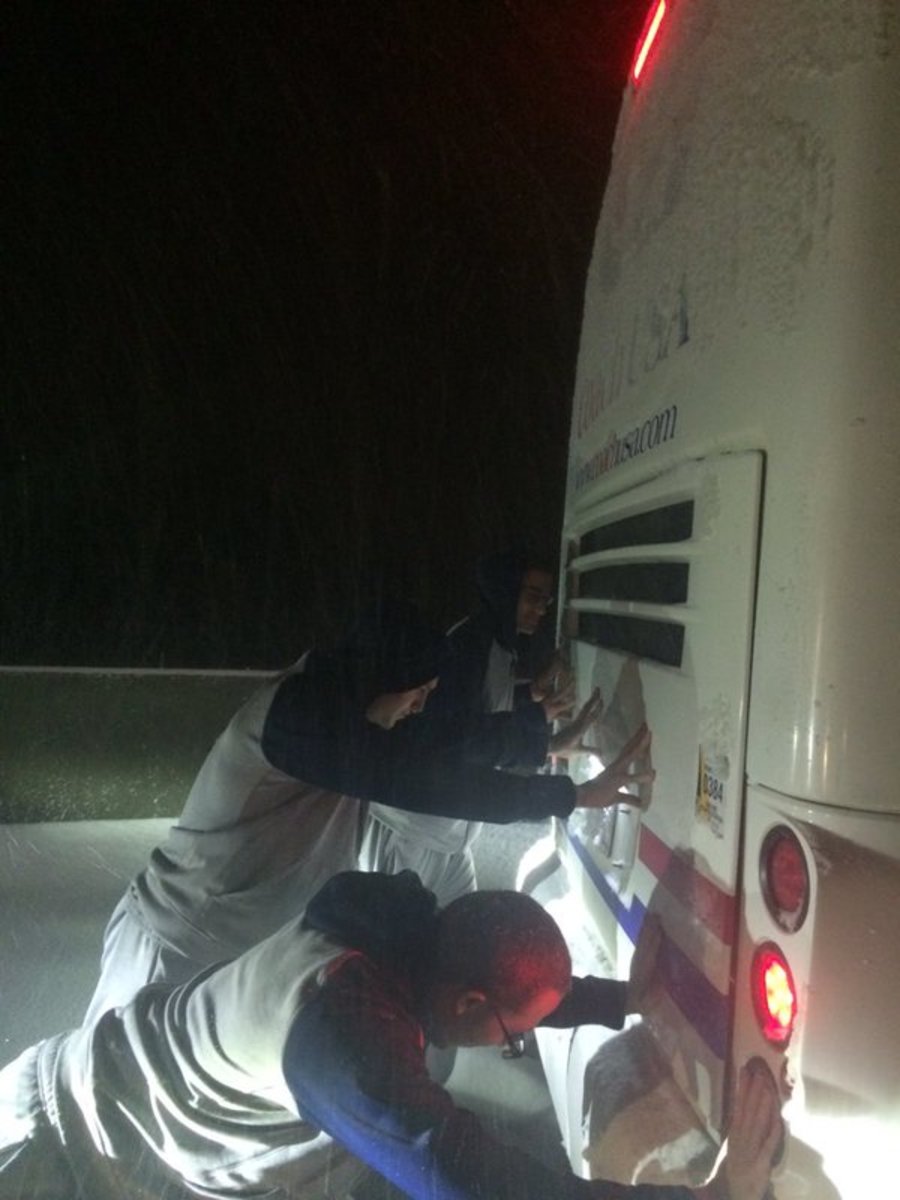 Duquesne basketball players push bus.