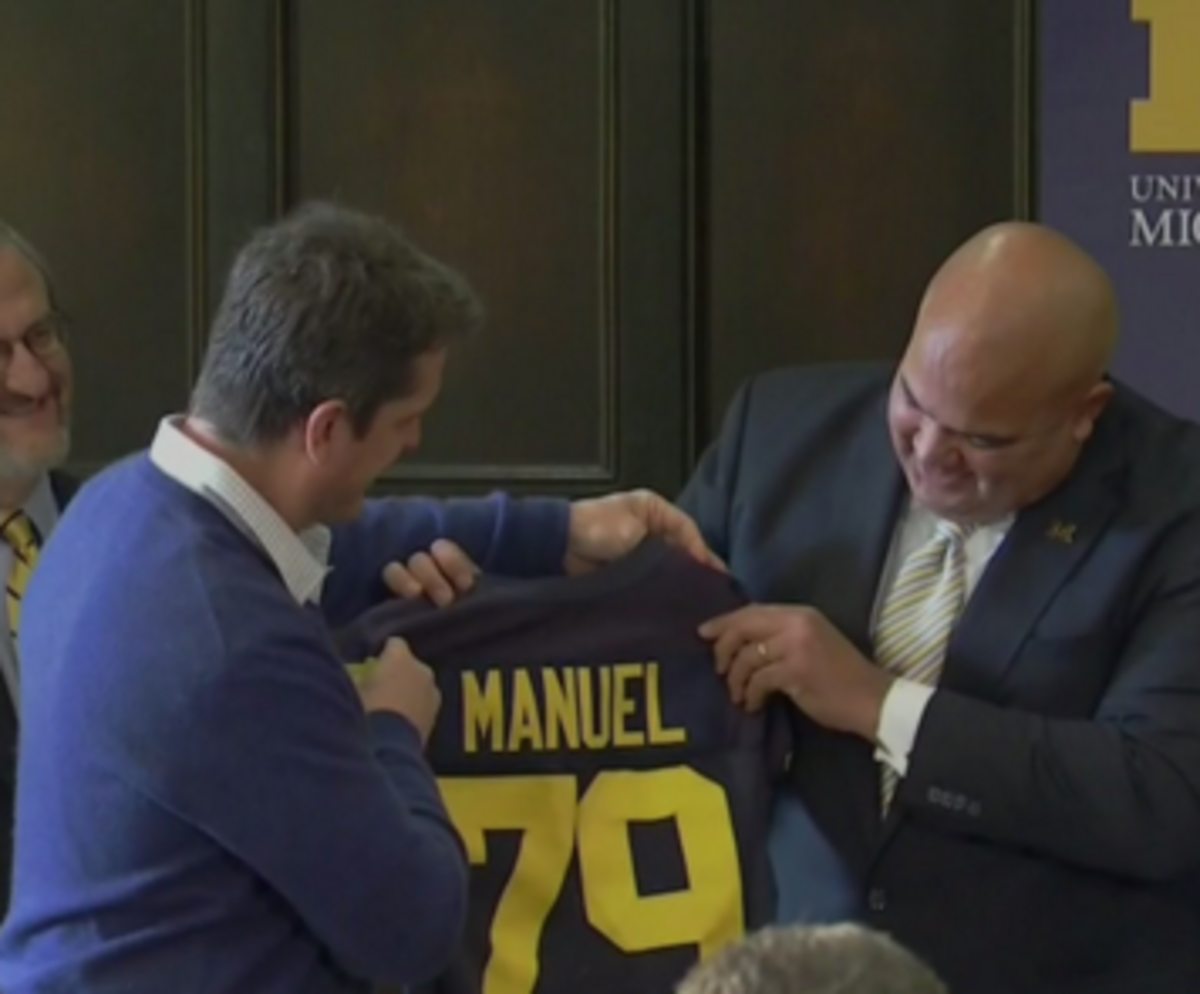 Warde Manuel and Jim Harbaugh hold a jersey.