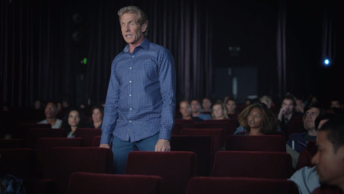 Skip Bayless standing up in a movie theatre.