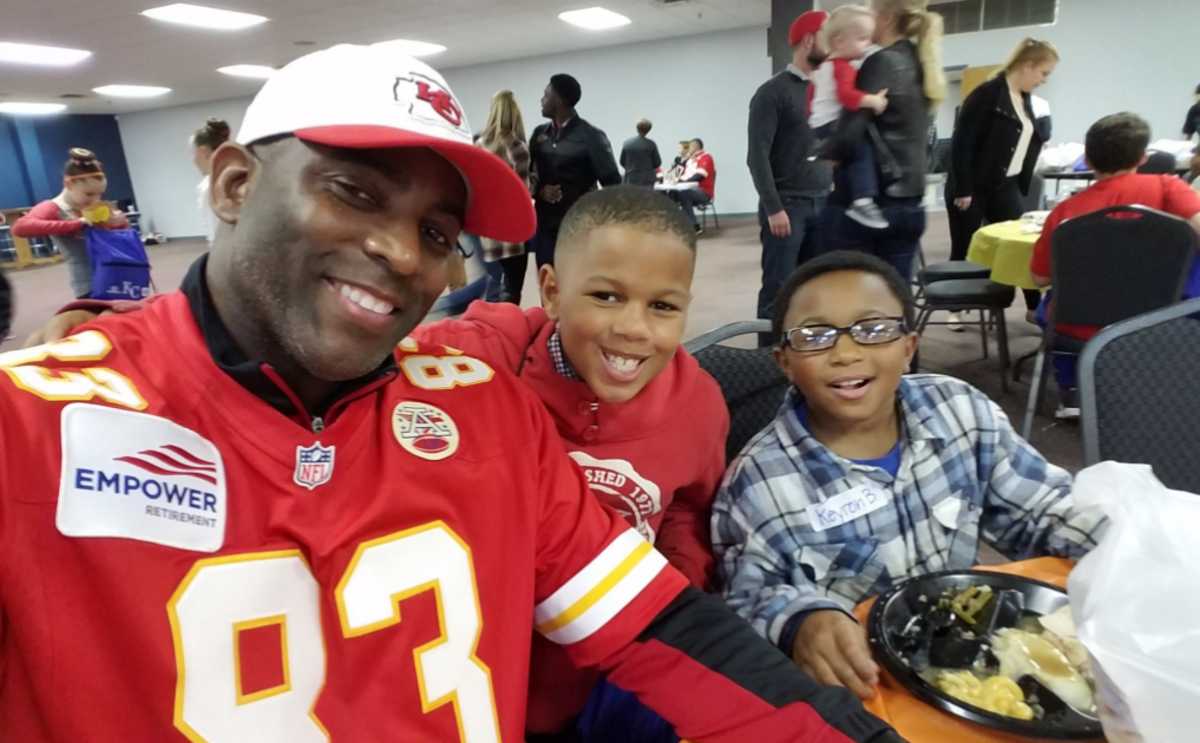 Danan Hughes smiling with children in a Chiefs jersey.