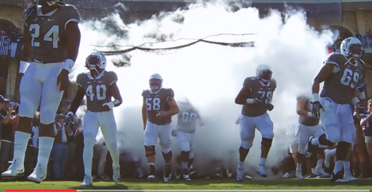 TCU football players running onto the field out of a smokey tunnel.