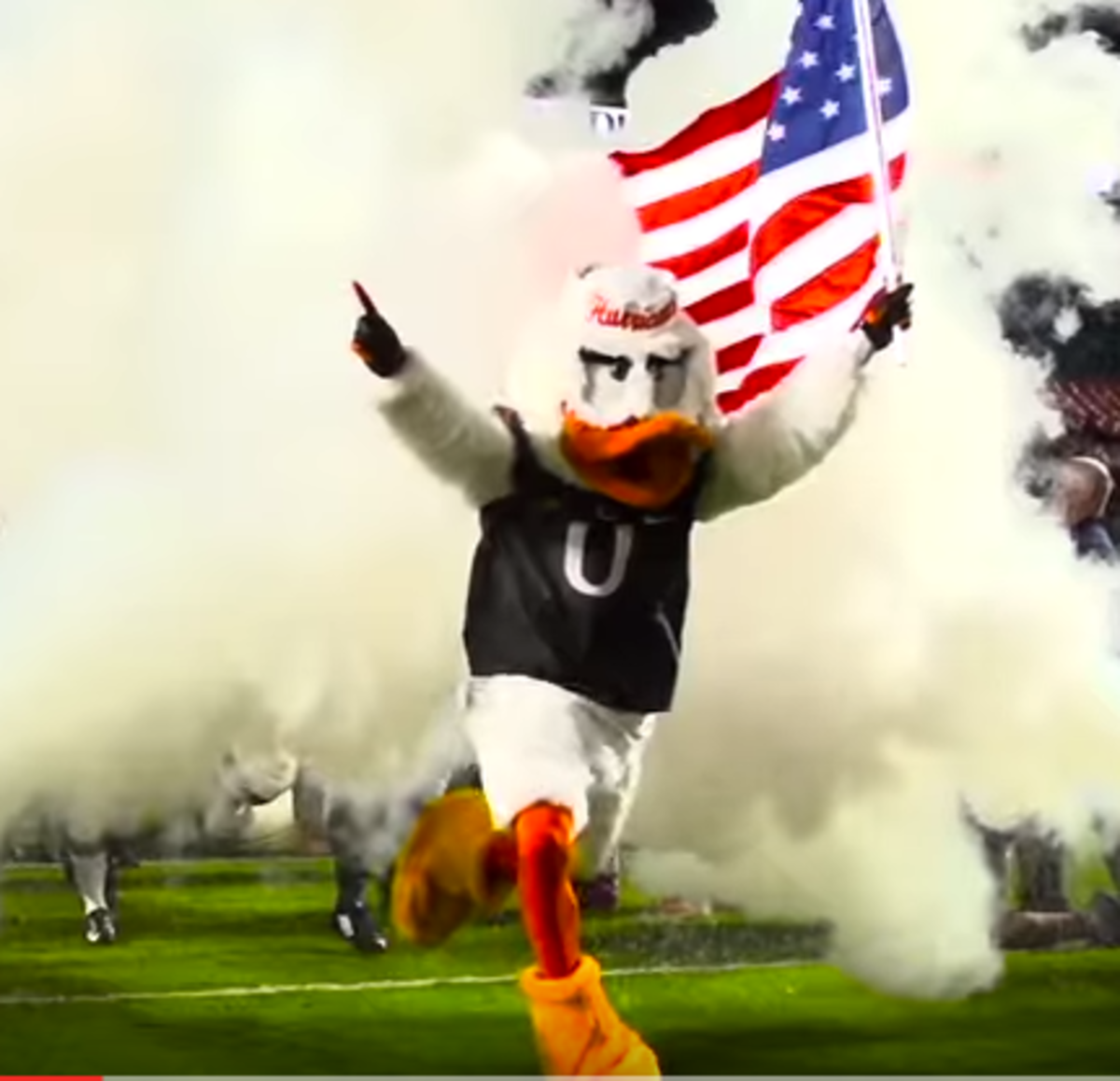 Miami mascot holds the American flag leading the team out of the tunnel.