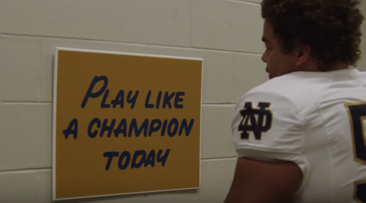 Notre Dame player standing in front of the "Play Like A Champion Today" sign.
