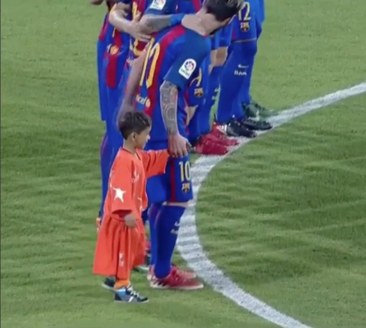 A young soccer fan holds hands with Lionel Messi.