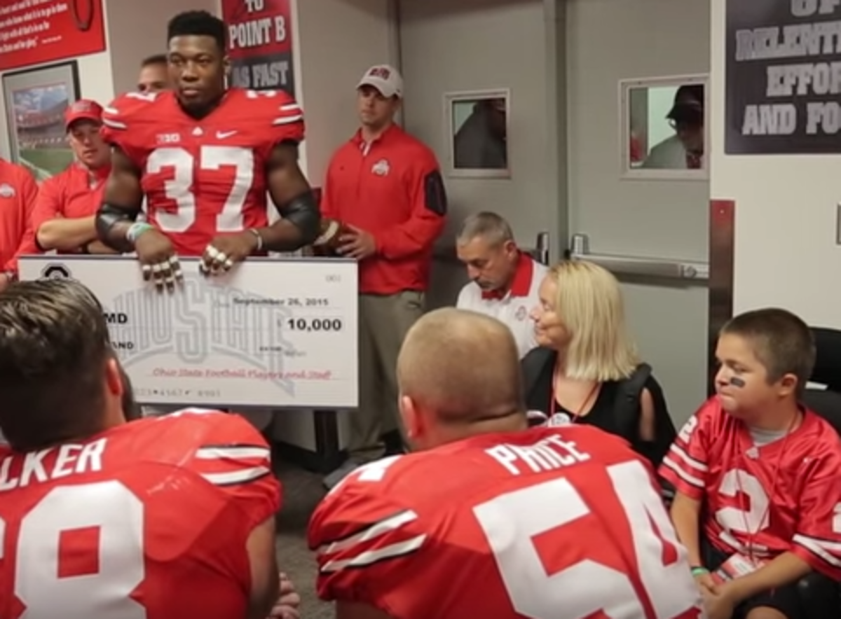 OSU players holding up a check for 10 thousand dollars for a boy with muscular dystrophy.