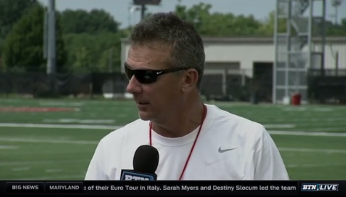 Urban Meyer speaking into a microphone for the Big Ten network.