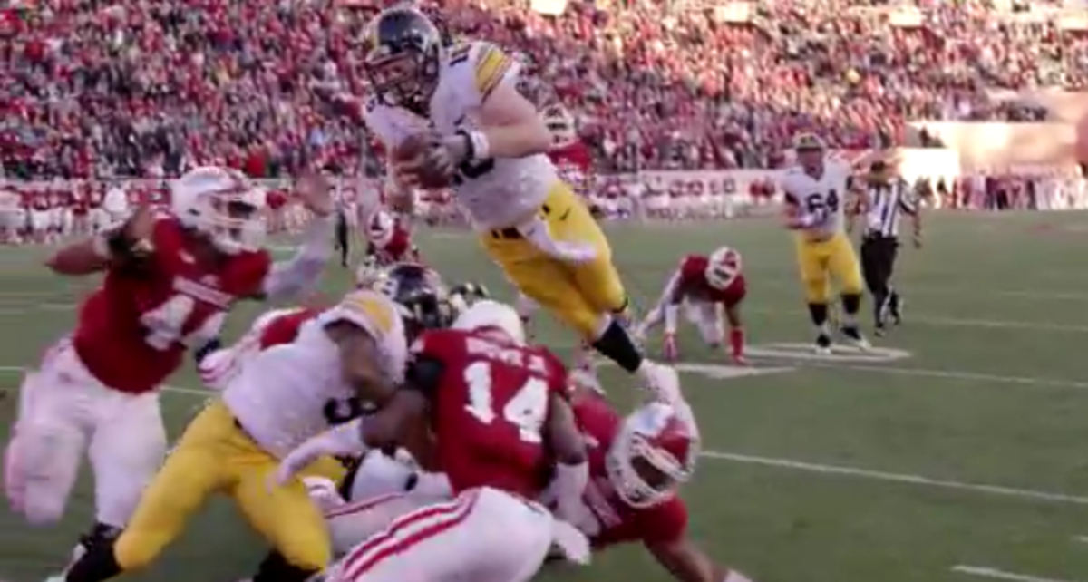 Iowa player jumps into the endzone over a crowd of players.
