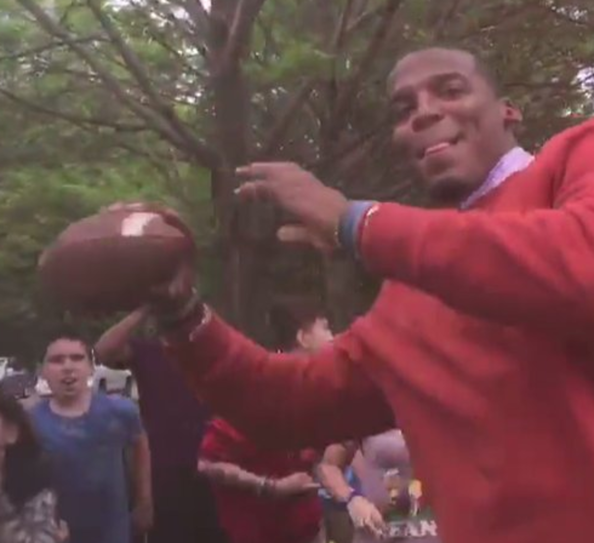 Cam Newton throws a football to middle schoolers.