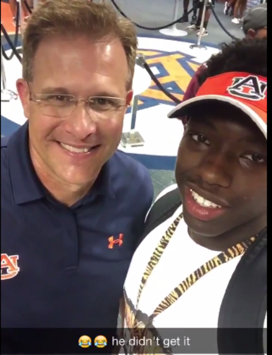 Auburn Recruit poses with Auburn football coach and takes video rather than selfie.