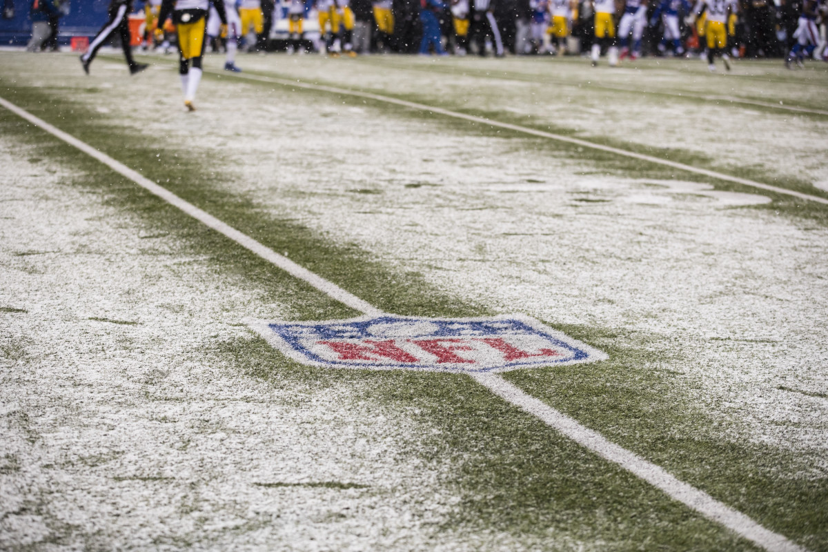 A detailed view of a freezing, snow covered NFL logo on the field.