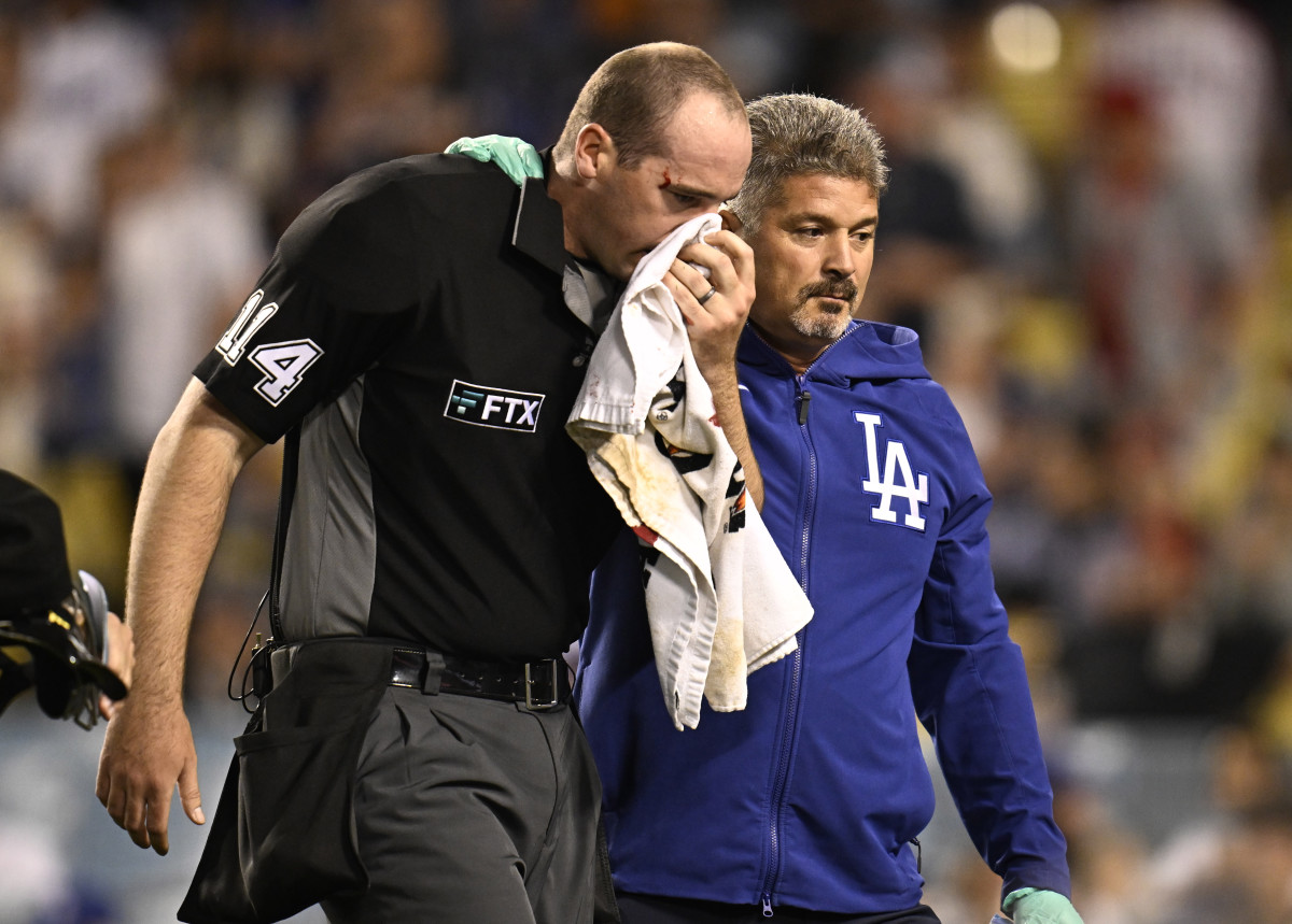 Los Angeles, CA - June 14:  Home plate umpire Nate Tomlinson is treated by Los Angeles Dodgers trainer Nathan Lucero after being hit in the face off a broken bat by Mike Trout (not pictured) of the Los Angeles Angels against the Los Angeles Dodgers in the ninth inning of a MLB baseball game at Dodger Stadium in Los Angeles on Tuesday, June 14, 2022. (Photo by Keith Birmingham/MediaNews Group/Pasadena Star-News via Getty Images)