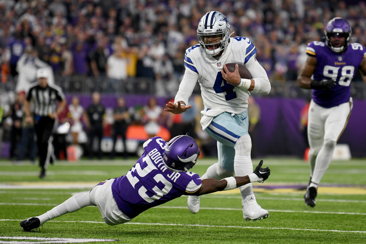 Dak Prescott running through a tackle by Andrew Booth Jr. of the Minnesota Vikings.